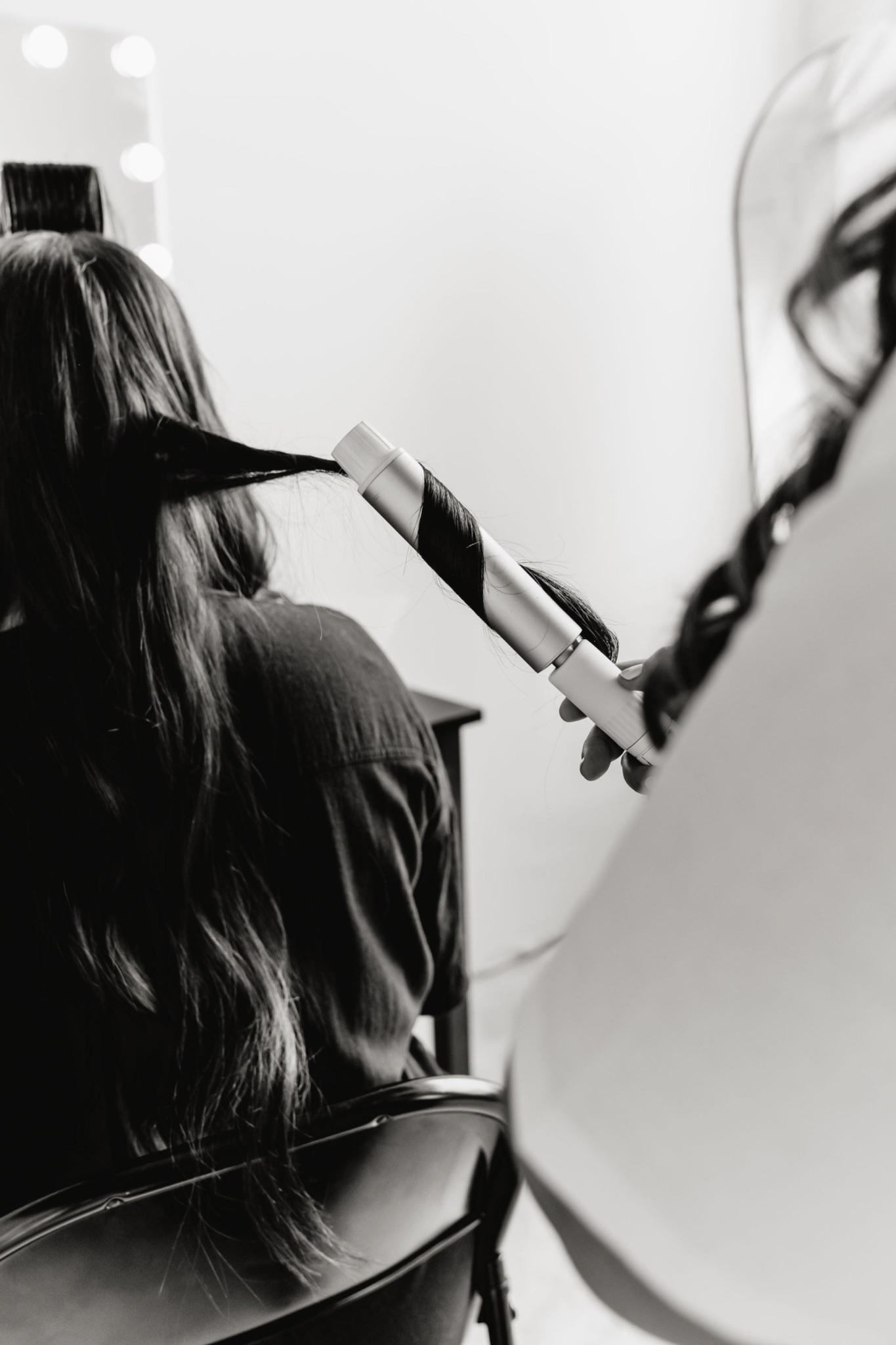 Bride having her hair styled into an elegant formal updo before her wedding